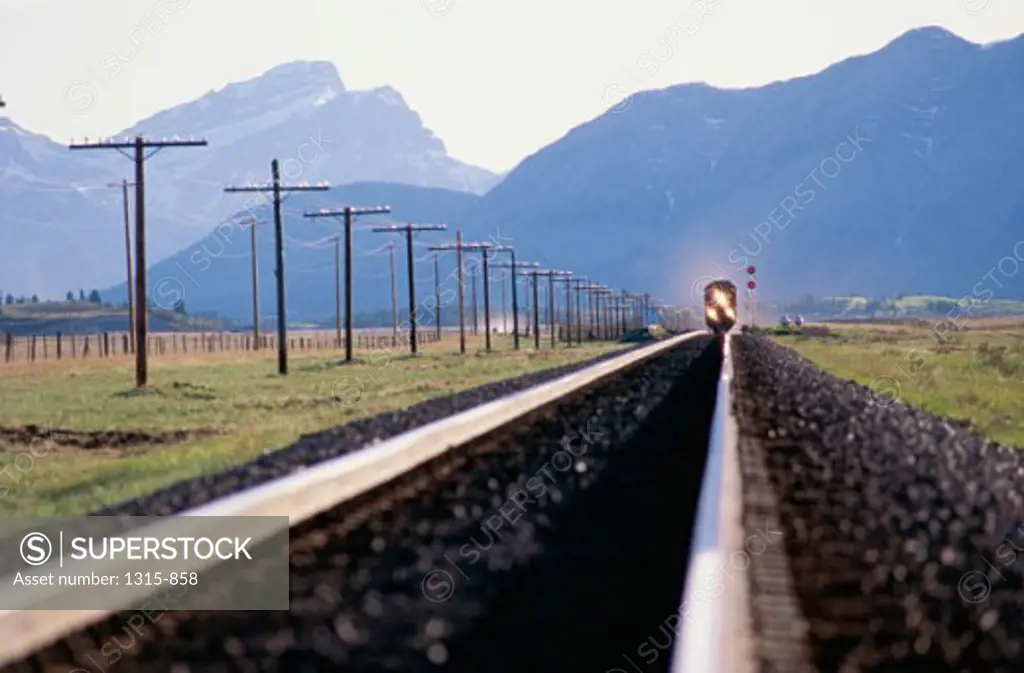 Train on a railroad track in front of mountains, Alberta, Canada