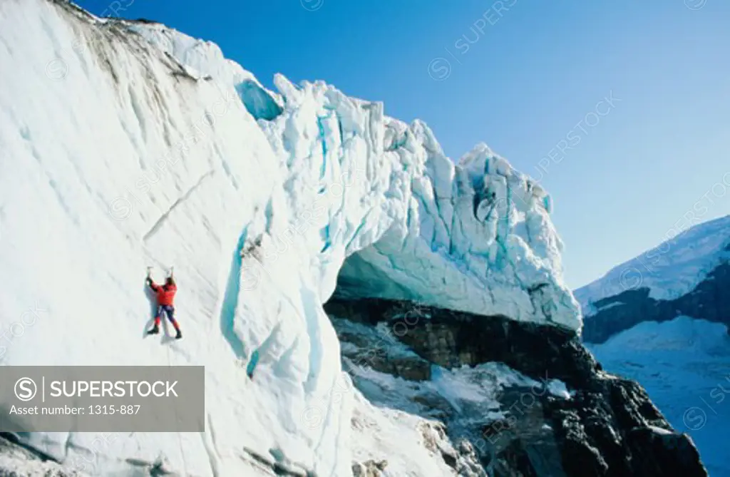 Rear view of a hiker climbing an ice covered cliff, Columbia Icefield, Alberta, Canada