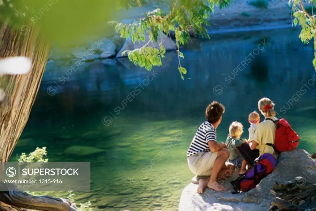 Family sitting on a rock at the bank of a river