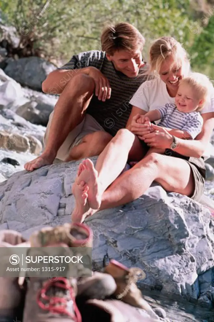 Mother and father sitting on a rock with a baby