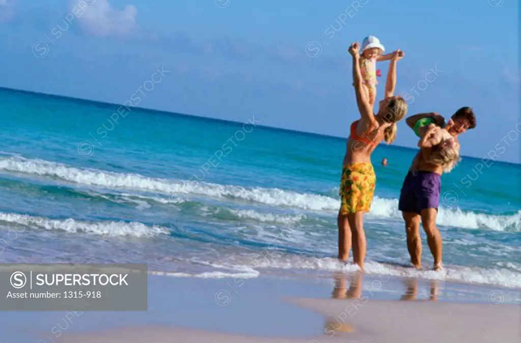 Parents playing with their son and daughter on the beach