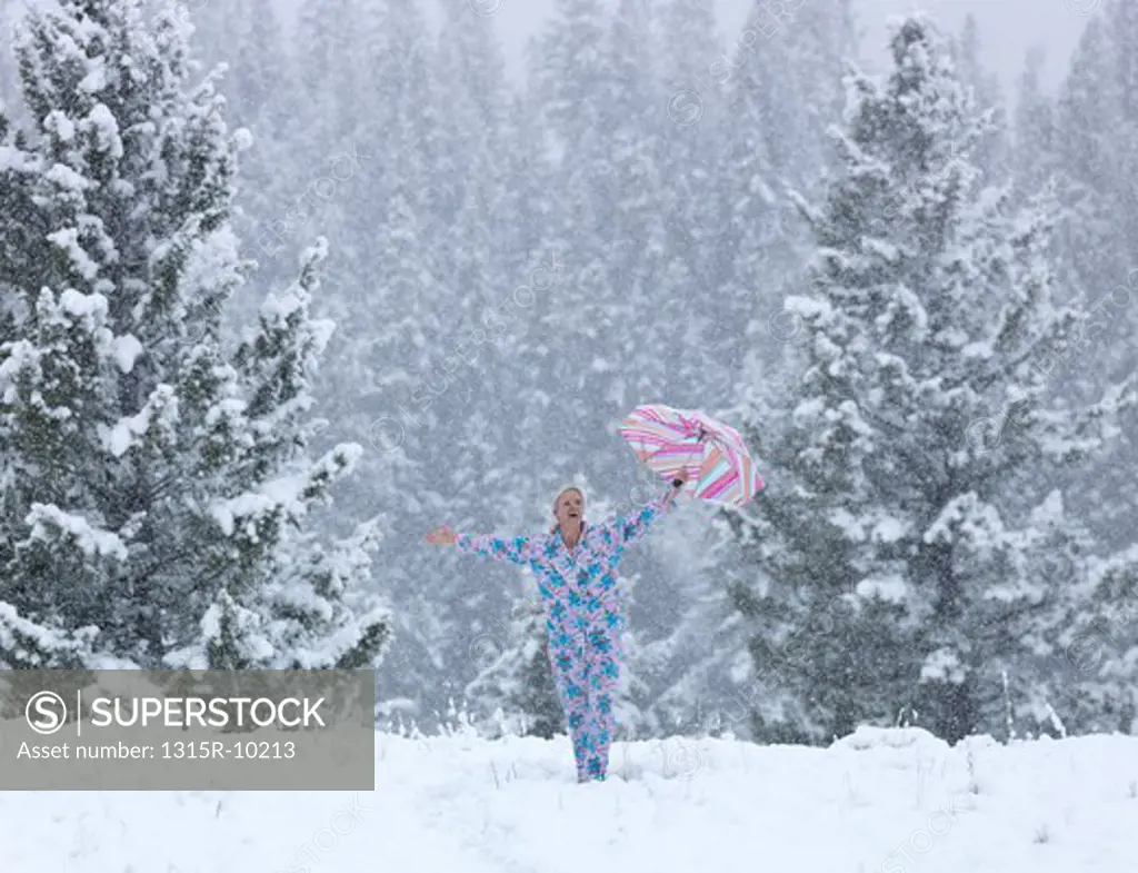 Canada, Alberta, Woman standing in snow and holding umbrella overhead