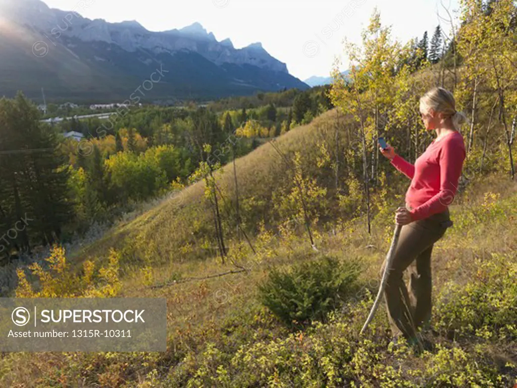 Canada, Alberta, Woman sending text message on hillside above Canmore