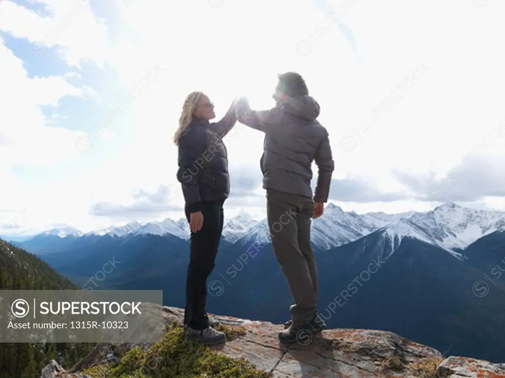 Canada, Alberta, Banff National Park, Couple exchanging high-fives on mountain summit