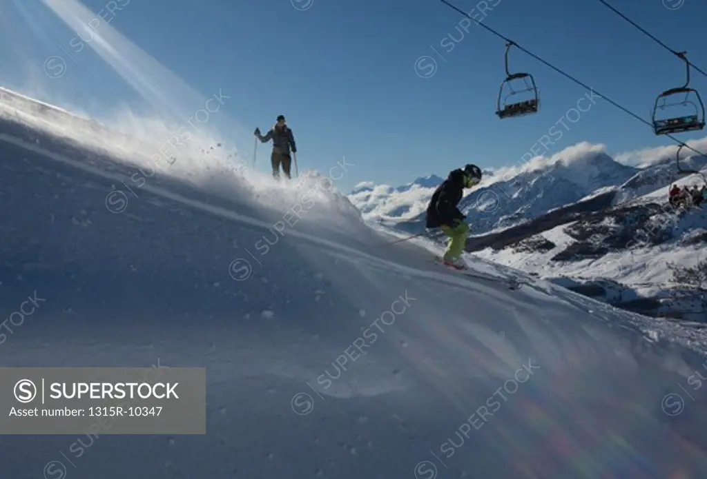 Italy, Piedmont, Sestriere, Teenage boy skiing down slope below chairlift