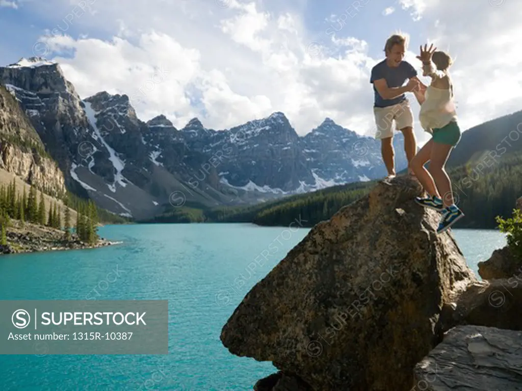 Canada, Alberta, Banff National Park, father and daughter standing on rock overlooking Moraine Lake