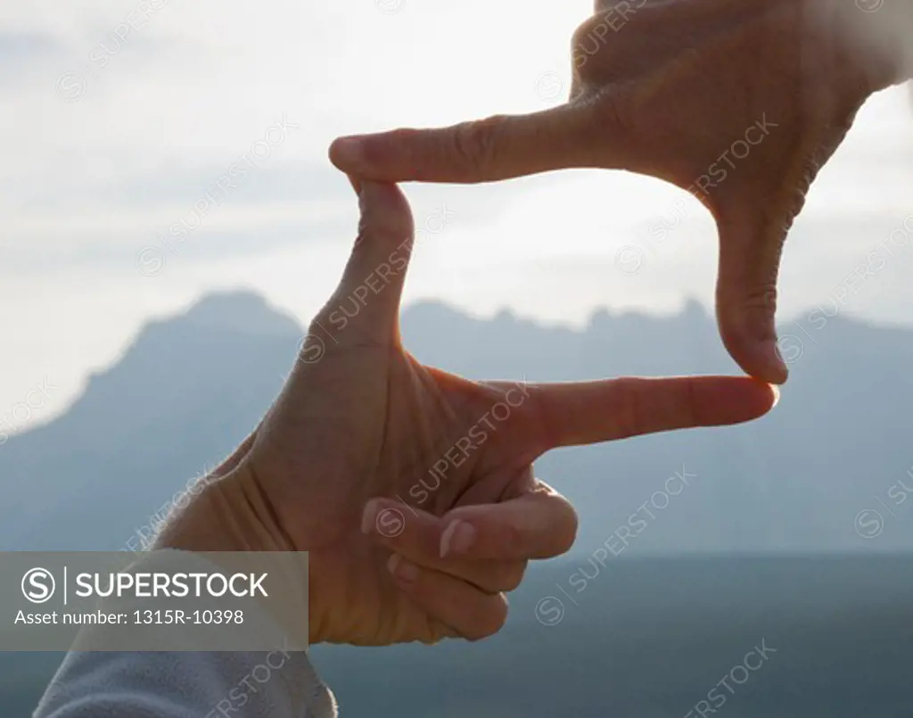 Canada, Alberta, Man's hands framing distant mountain landscape