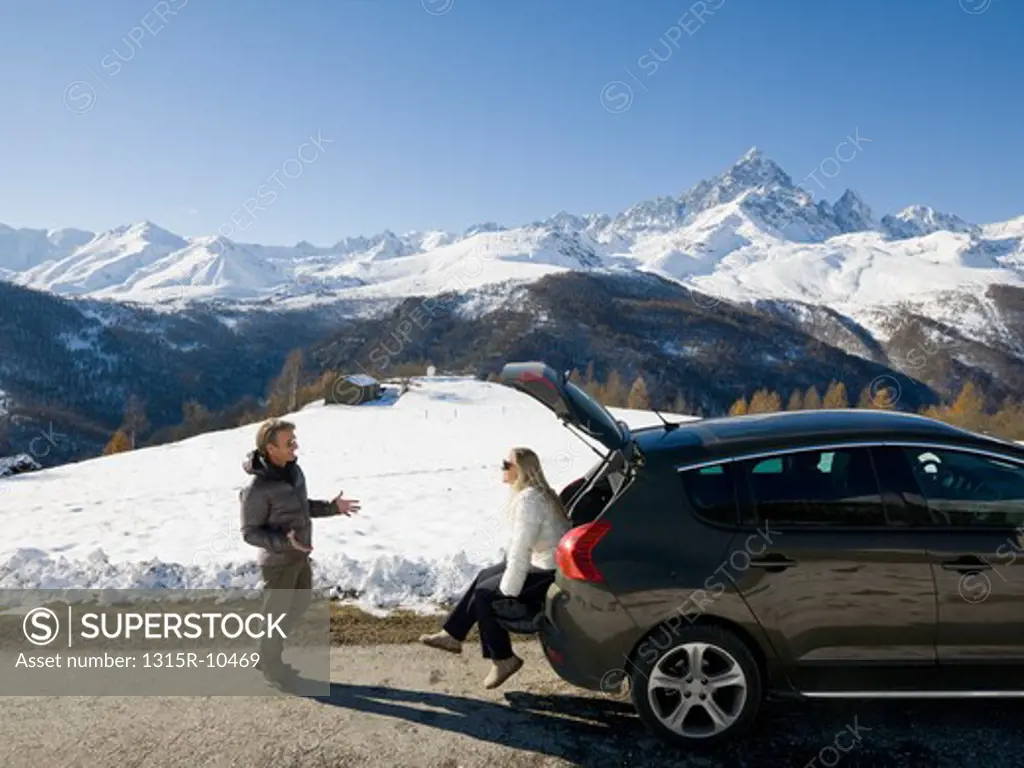 Italy, Piedmont, Couple resting in back of car on mountain road