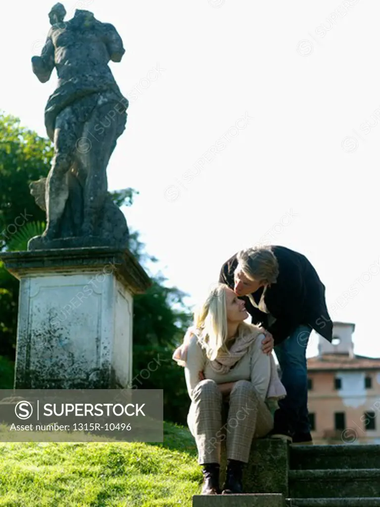 Italy, Piedmont, Stresa, Lake Maggiore, Couple kissing beside headless statue