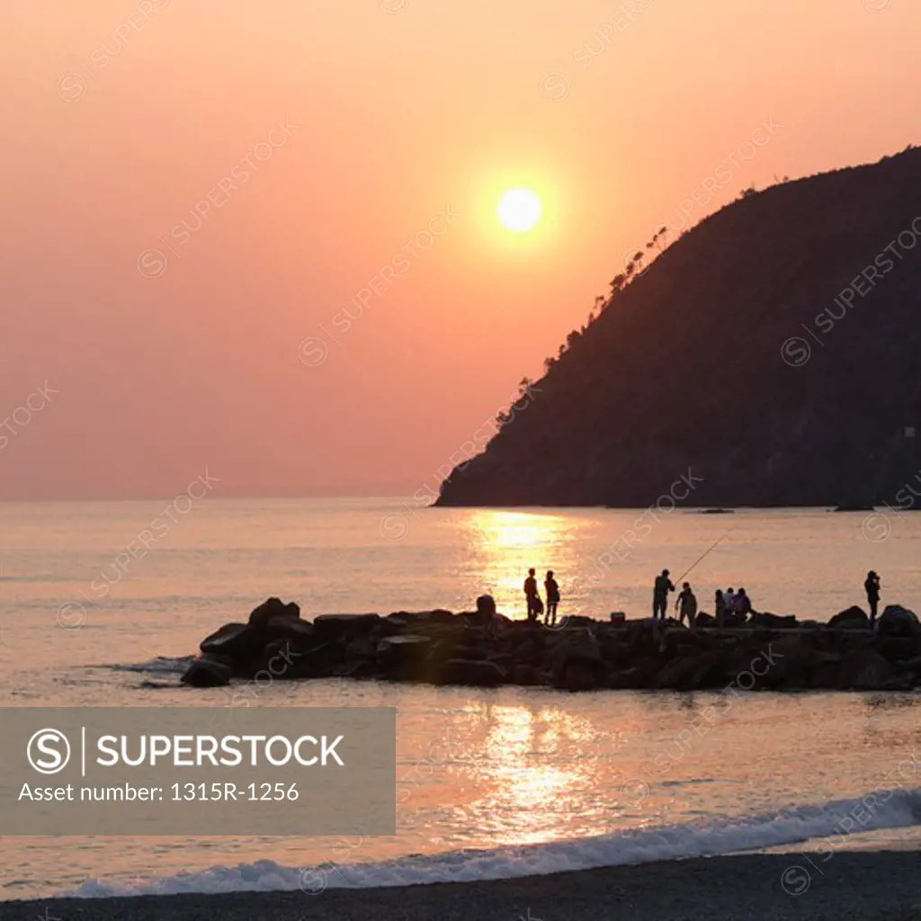 Italy, Liguria, Levanto, People fishing and standing on rock breakwater