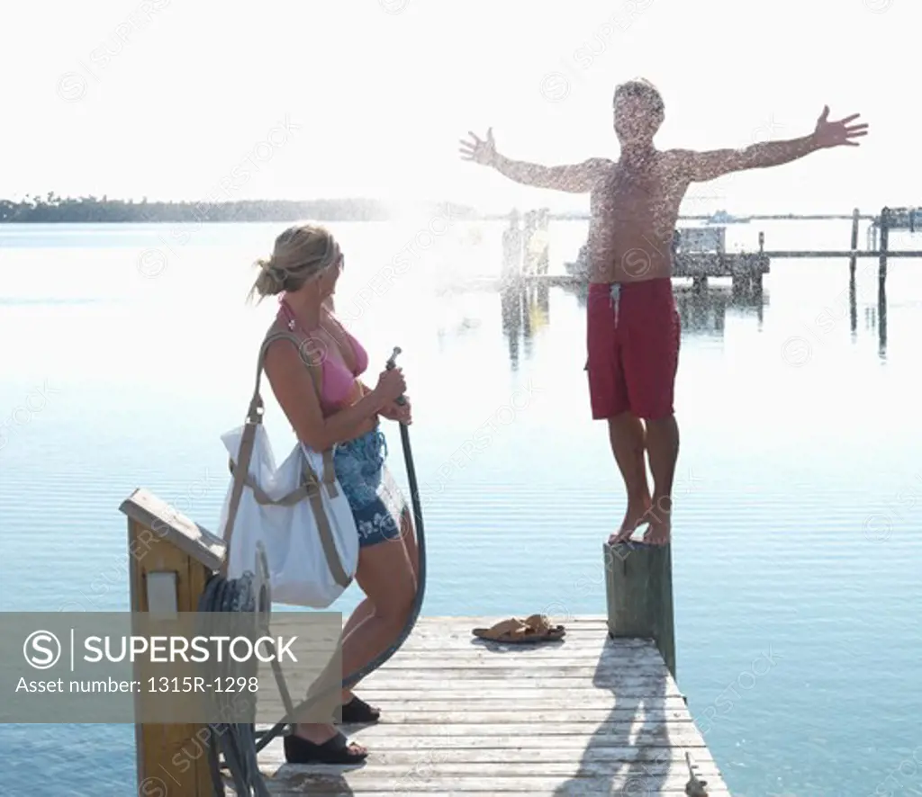 USA, Florida Keys, Islamorada, couple playing with water spray on pier