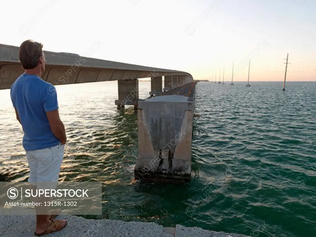 USA, Florida Keys, Islamorada, man looking across water from broken bridge