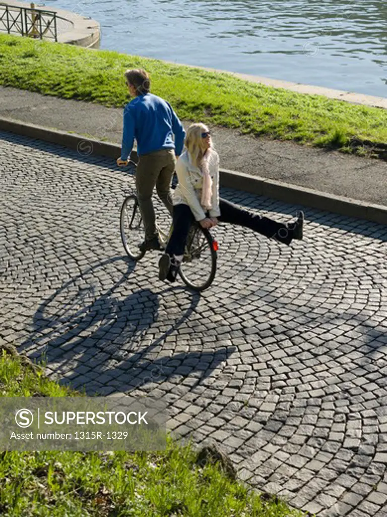 Italy, Piedmont, Turin, Couple on bicycle on cobblestone path