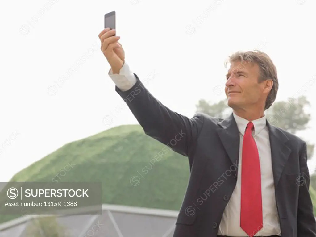 Italy, Piedmont, businessman taking picture with cell phone outside green dome