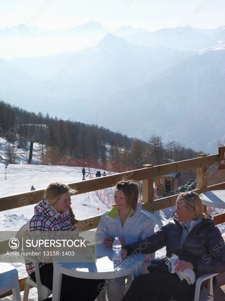 Italy, Piedmont, Bardonecchia, teenage girls and mother having lunch at outdoor cafe