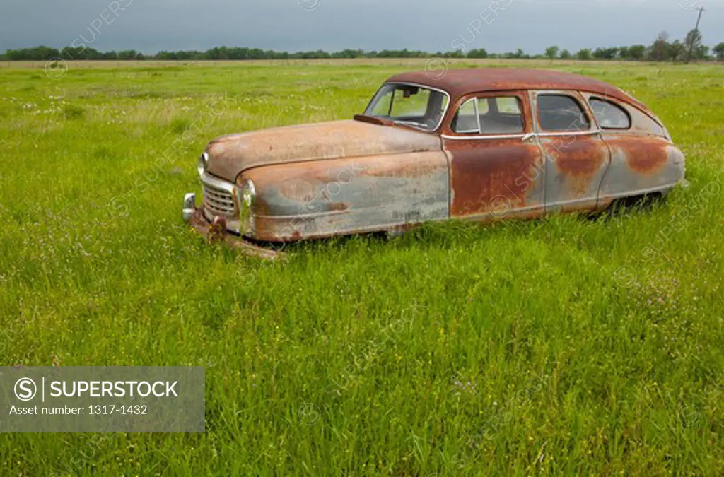 Old car rusting away in a field