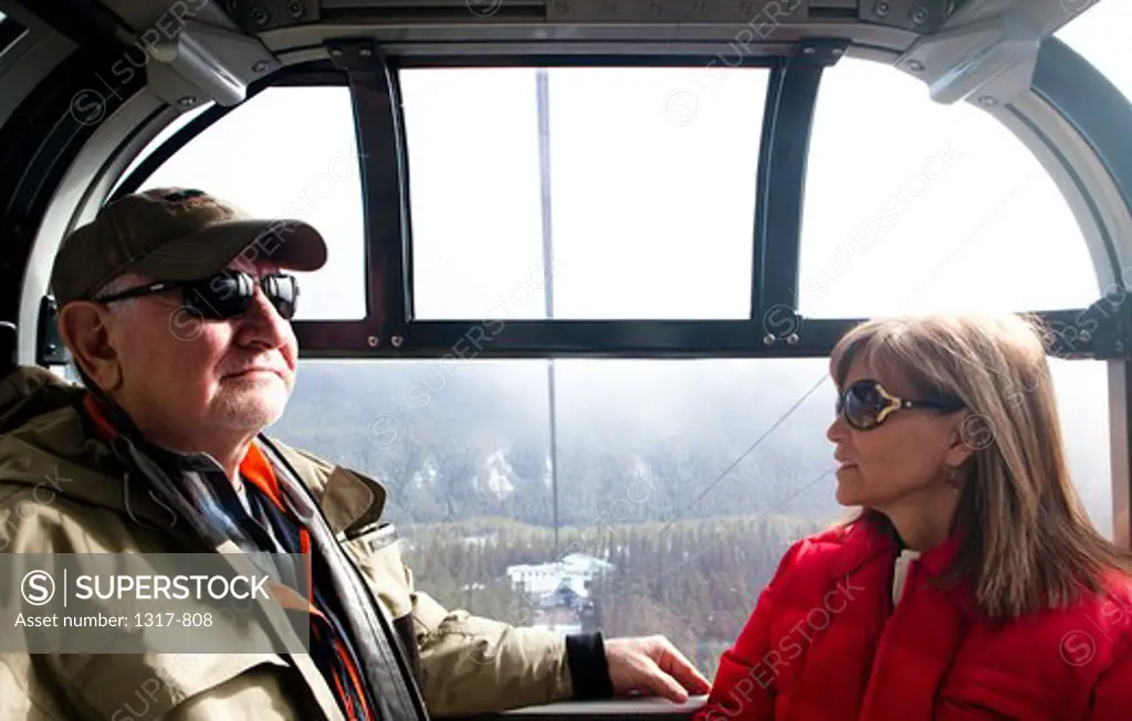Couple sitting in a gondola, Sulphur Mountain, Banff National Park, Alberta, Canada