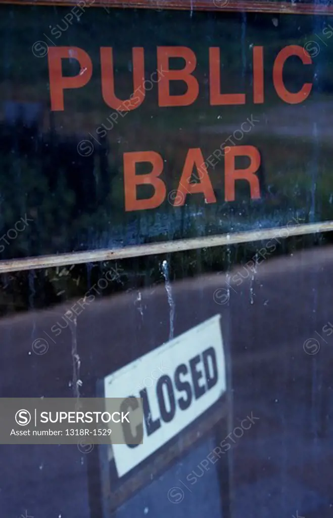 UK, Wales, Dyfed, Detail of dirty window with reflection of road and signs inside stating Public Bar and Closed