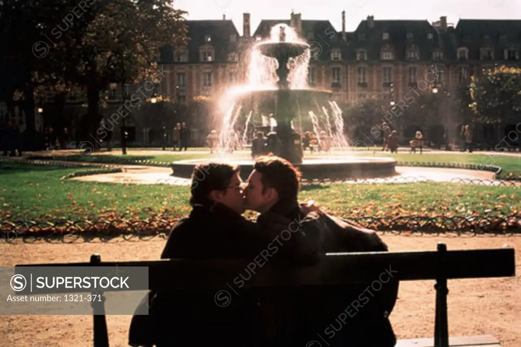 Rear view of a young couple kissing in a garden, Place des Vosges, Paris, France