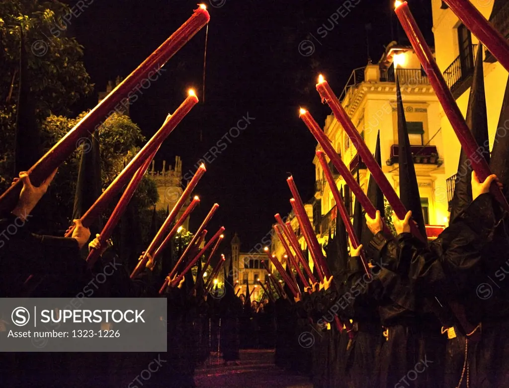 Spain, Seville, Low angle view of Nazarenes holding their Cirios