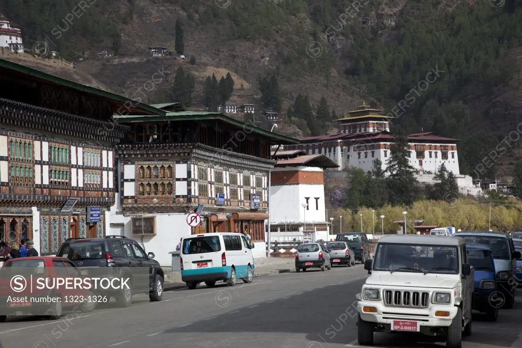 Cars parked at roadside with dzong in the background, Paro Dzong, Paro, Bhutan