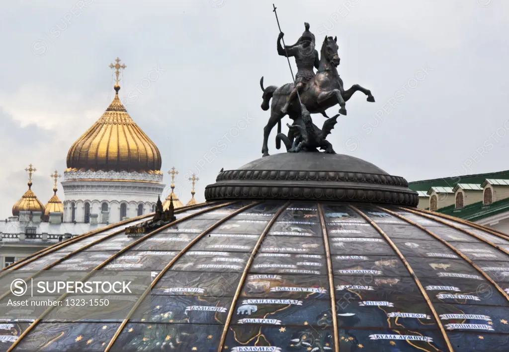 Monument on a glass cupola to Saint George and the Dragon with church in the background, Manezhnaya Plaza, Cathedral of Christ The Saviour, Moscow, Russia