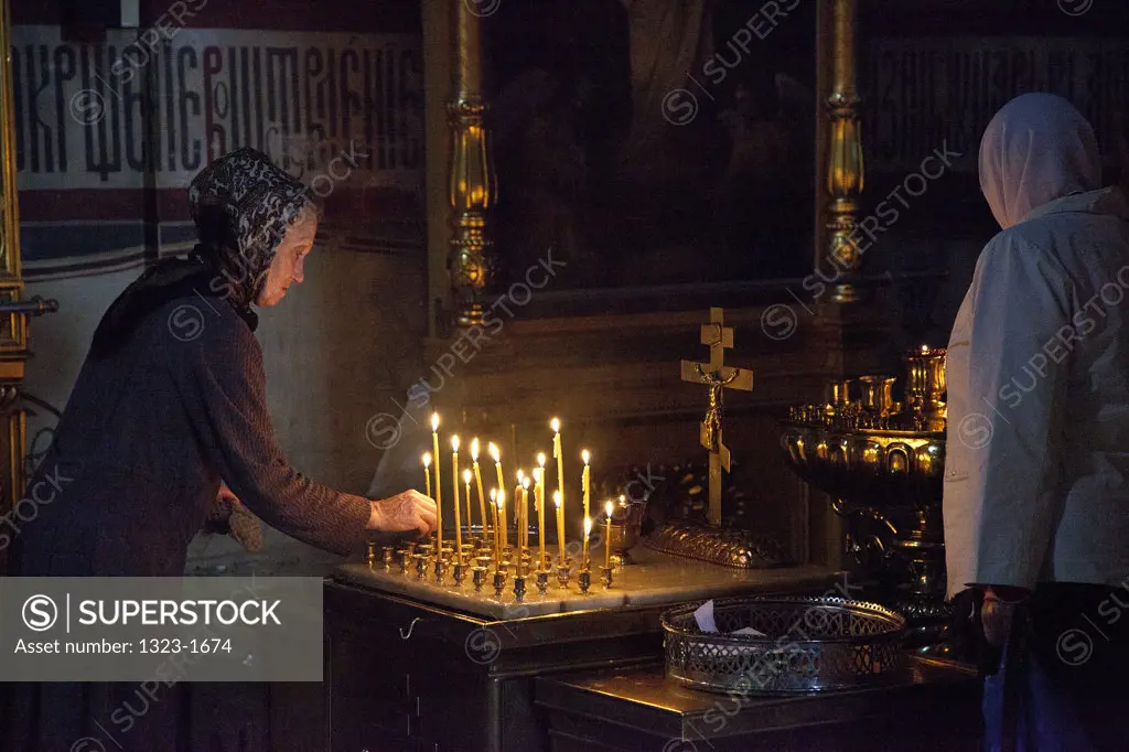 Women lighting candles inside the Assumption Cathedral, St. Sergius Monastery, Sergiyev Posad, Moscow Oblast, Russia
