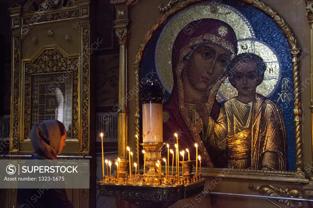 Woman and candles inside the Assumption Cathedral, St. Sergius Monastery, Sergiyev Posad, Moscow Oblast, Russia