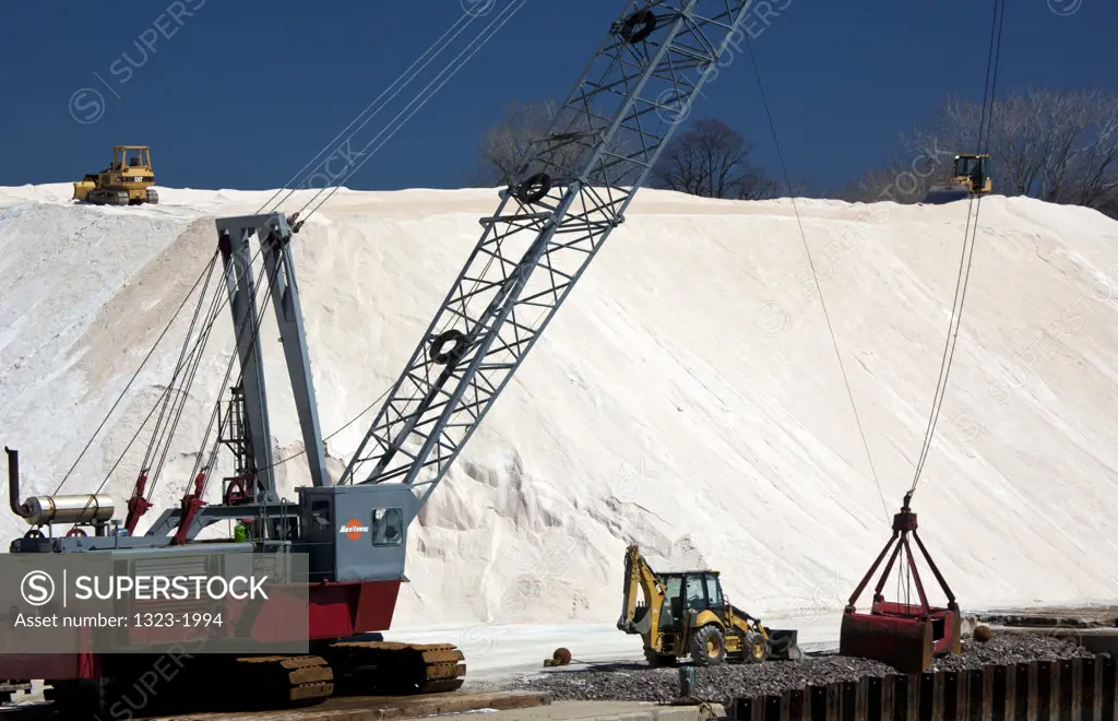 USA, Massachusetts, Boston, Bulldozers and crane in front of large salt mound