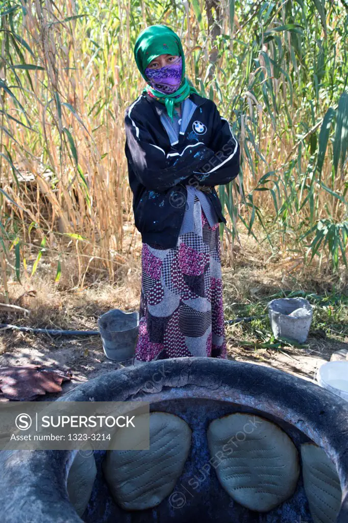 Turkmenistan, Bogurdak, Turkmen girl baking bread in Tamdyr clay oven