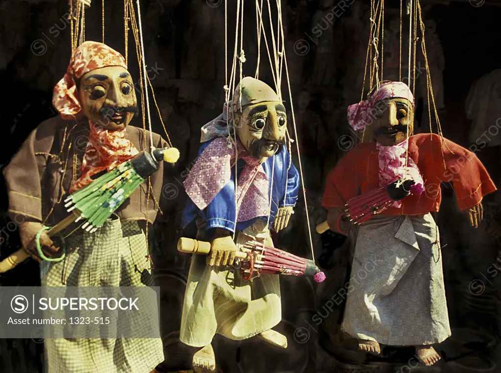 Close-up of three puppets hanging on strings