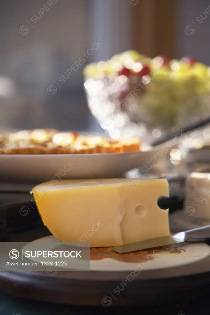 Close-up of wedge of Swiss cheese with other food on a plate