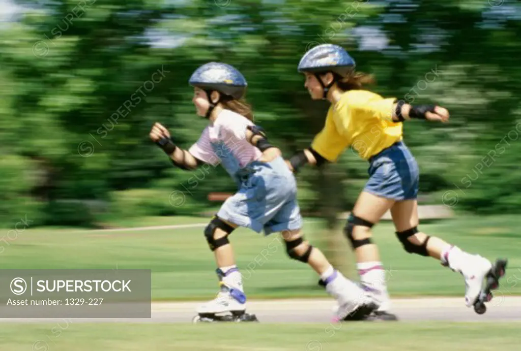 Side profile of two girls inline skating on a road