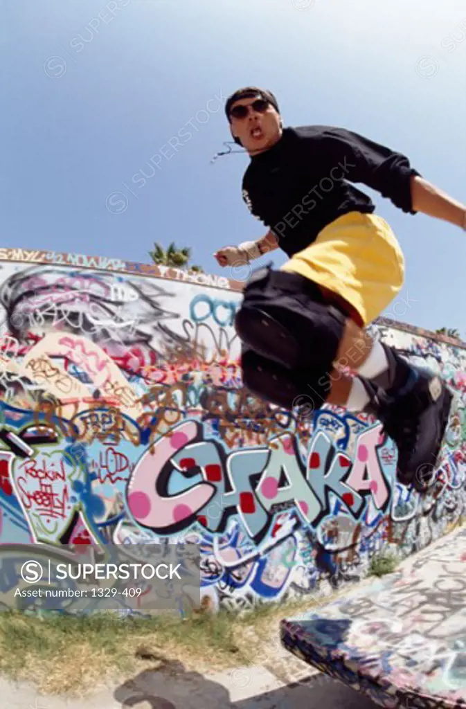Low angle view of a young man performing stunts with inline skates