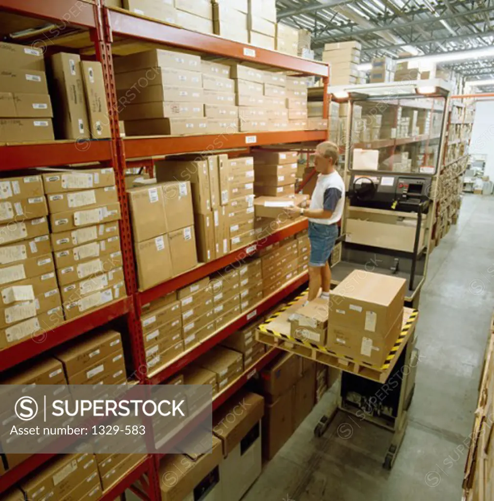 Side profile of a mid adult man placing boxes on shelves in a warehouse