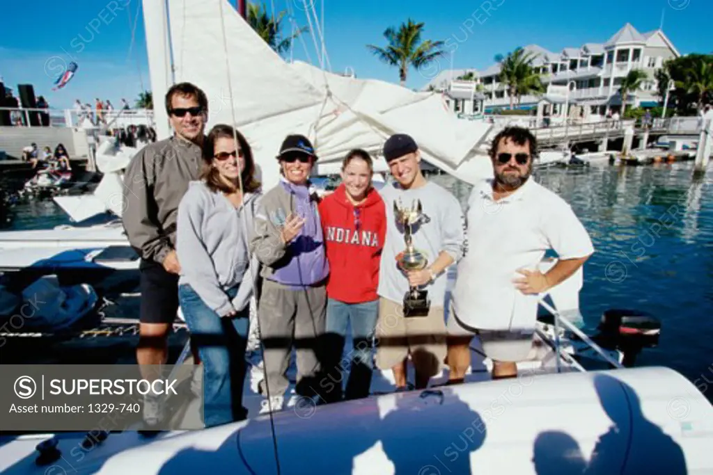Sports team on a boat with a member holding a trophy