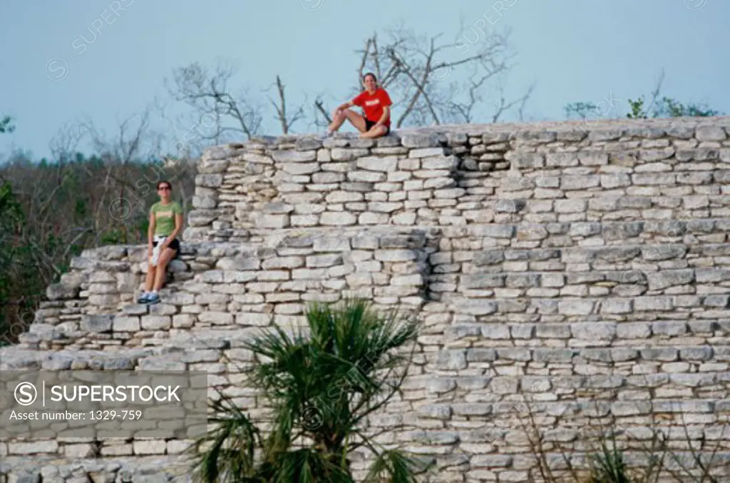 Young couple sitting on a stone wall, Mayan Ruins, Mexico