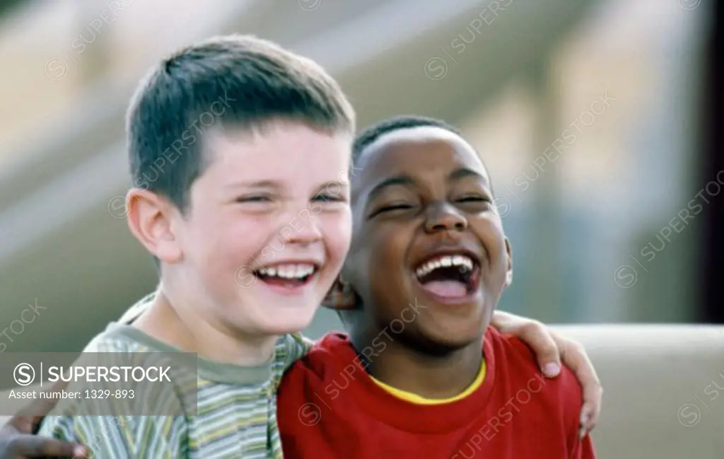 Close-up of two boys sitting on a couch smiling