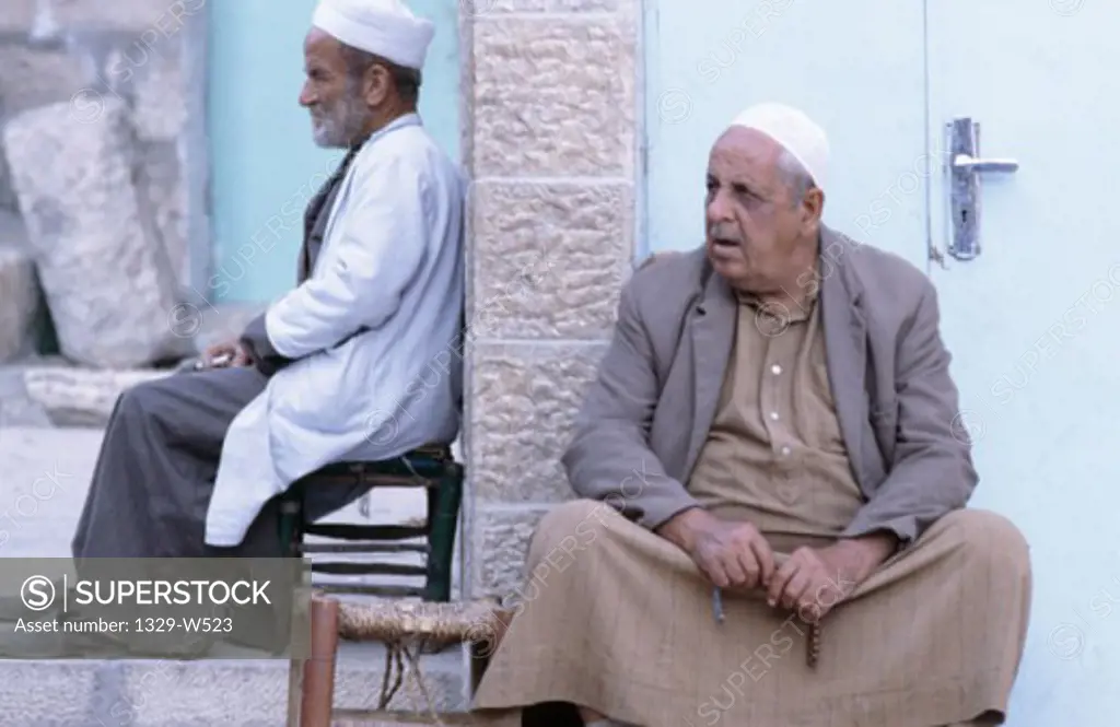 Two senior men sitting against a wall, Jerusalem, Israel