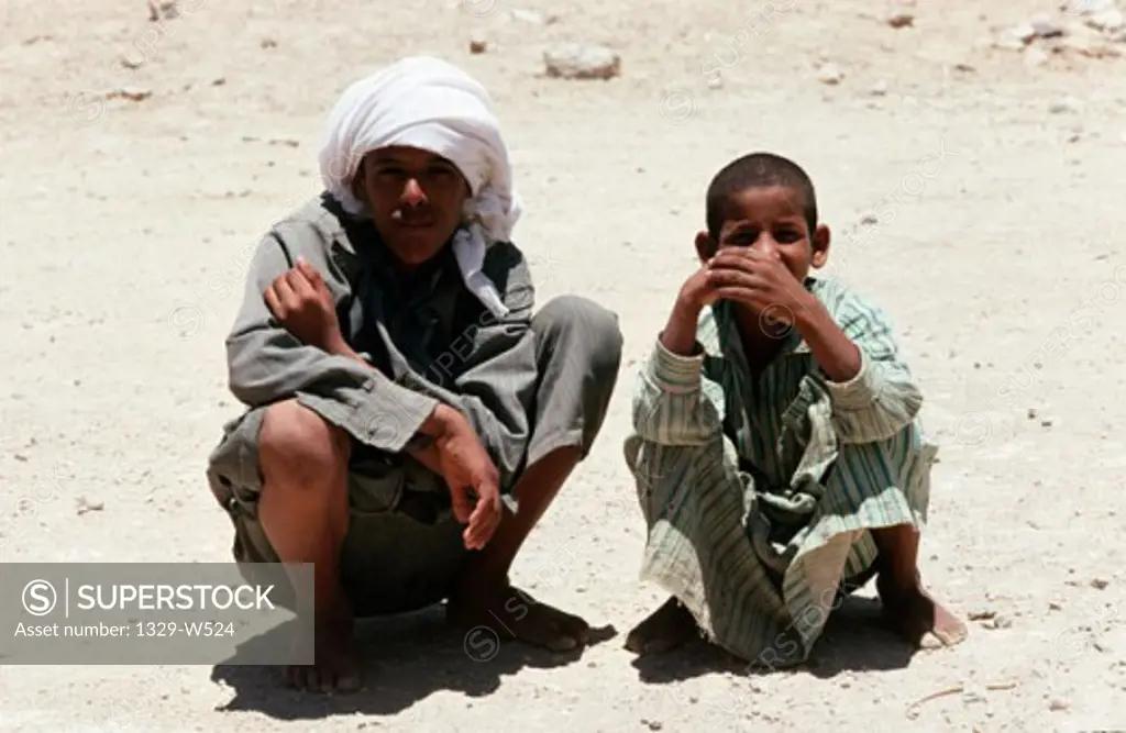 High angle view of a father and his son squatting, Bedouin, Sinai Desert, Egypt
