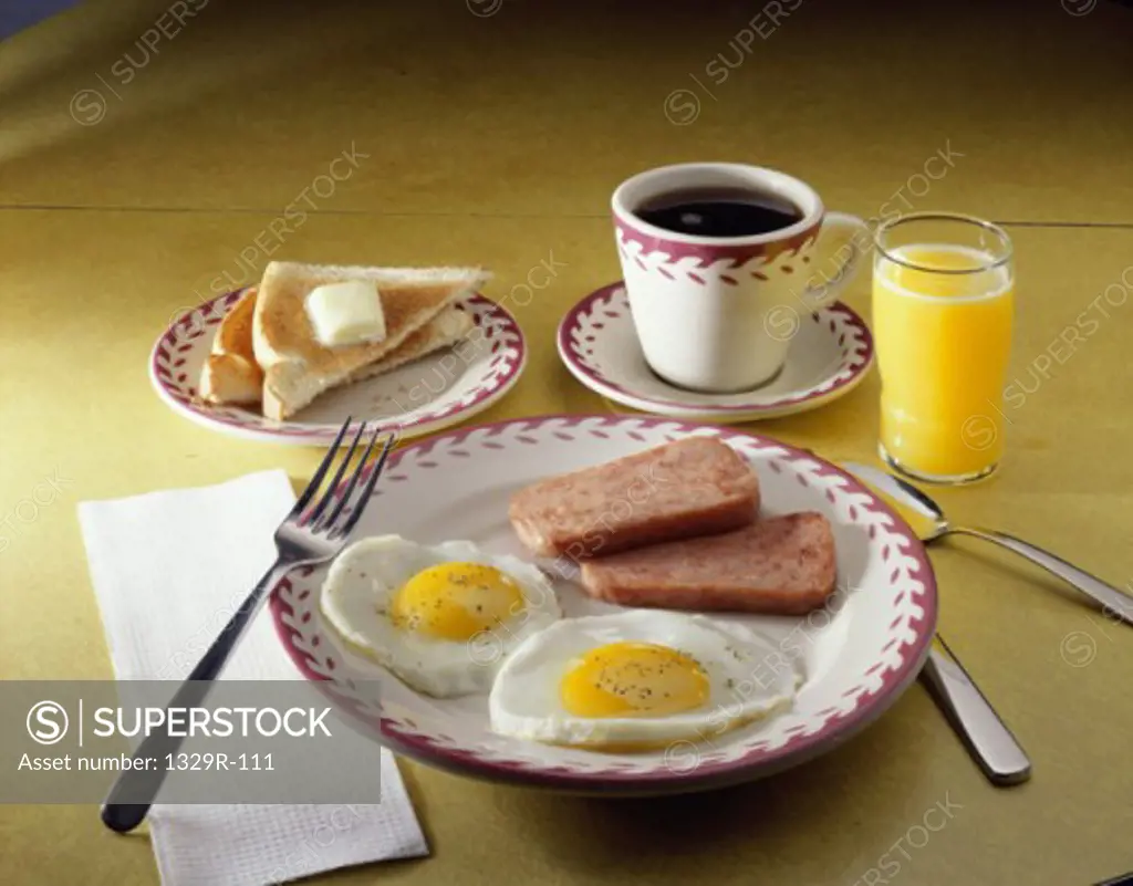 Cup of coffee with a plate of fried eggs and spam