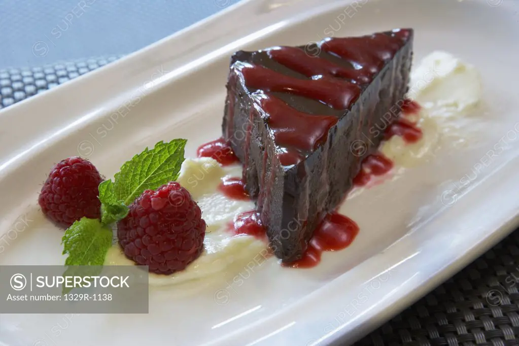 Chocolate brownie dessert with raspberry sauce and fresh raspberries on a white plate