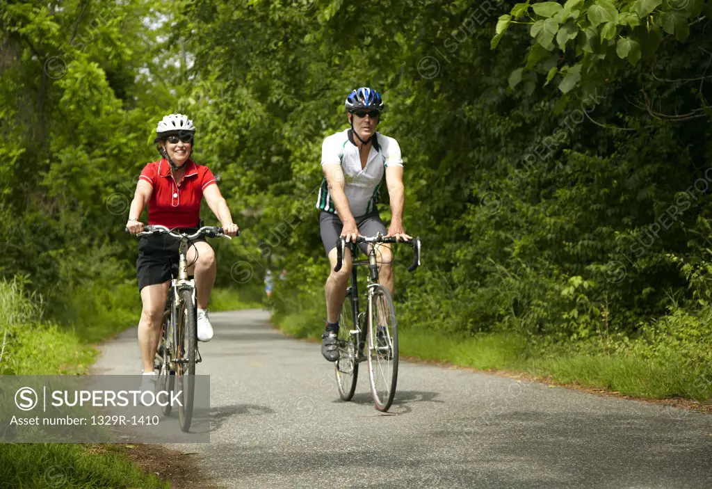 Man and woman leisurely riding bikes on path through woods