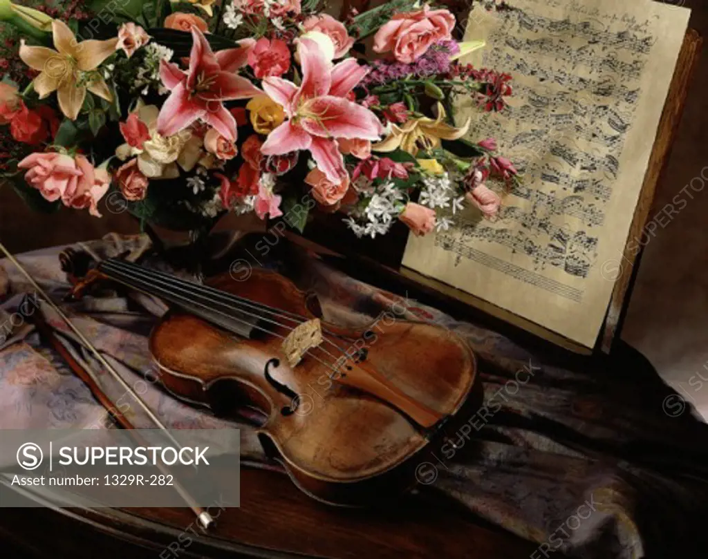 Violin and a bow near a vase of flowers and sheet music