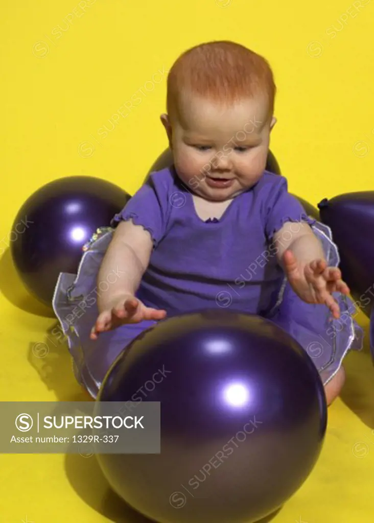 Baby girl sitting among balls