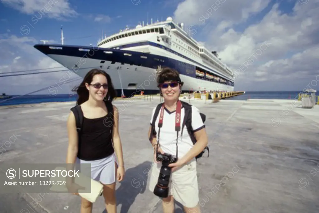 Two mid adult women standing in front of a cruise ship