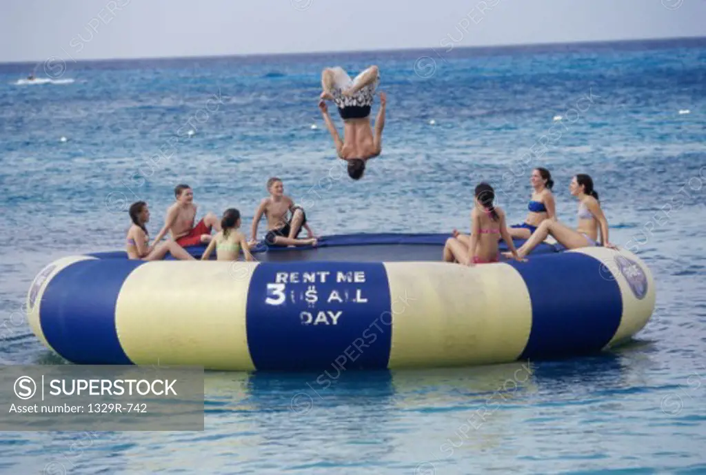 Teenage girls and teenage boys on a trampoline in the sea