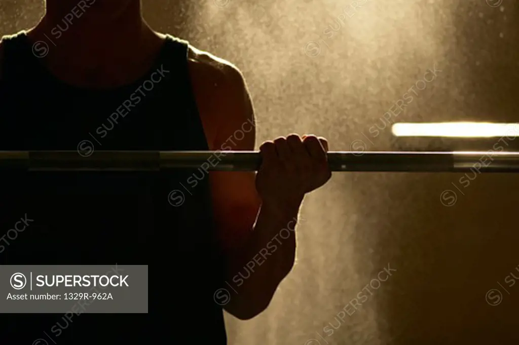 Mid section view of a man exercising with a barbell