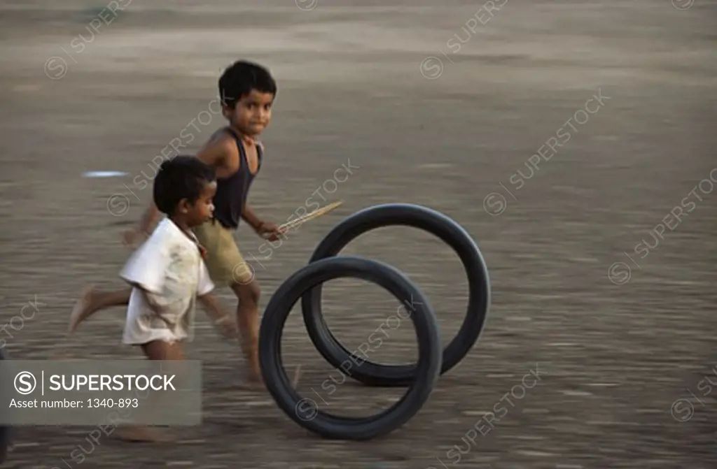 Two boys playing with tires, Tamil Nadu, India