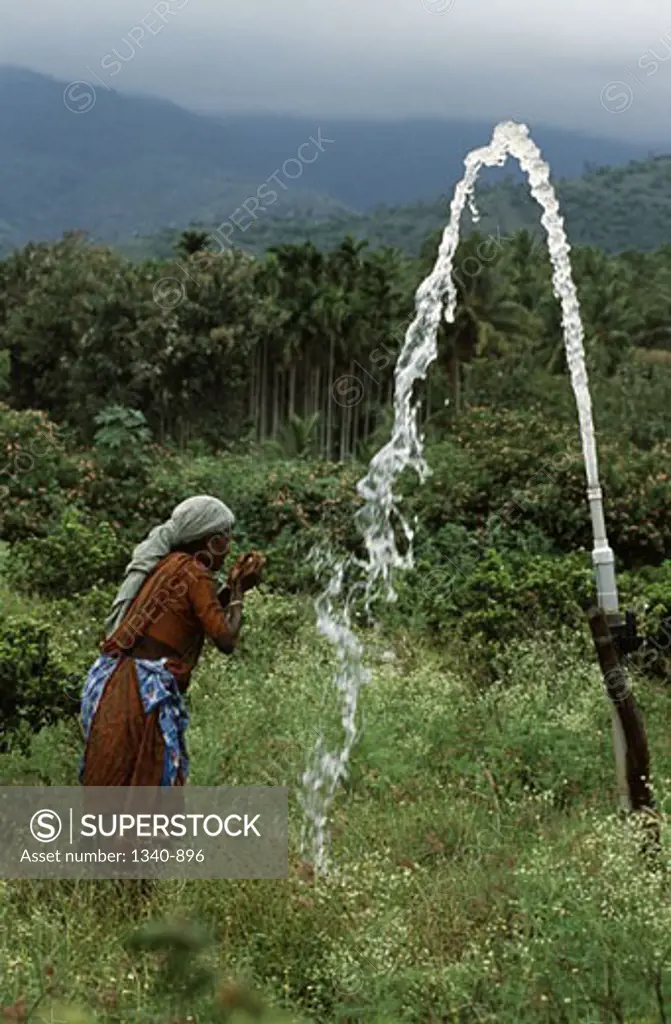 Side profile of a mature woman drinking water, Attappadi, Palakkad District, Kerala, India